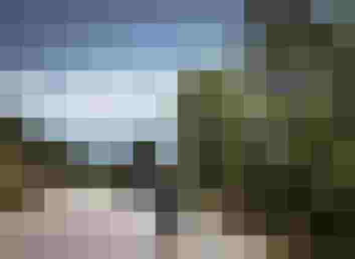 Motorradfahrer auf kurviger Alpenstraße mit Blick auf Berge und grüne Wälder