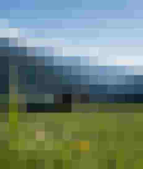 Holzhütte auf grüner Wiese mit Blick auf verschneite Berge der Hohen Tauern