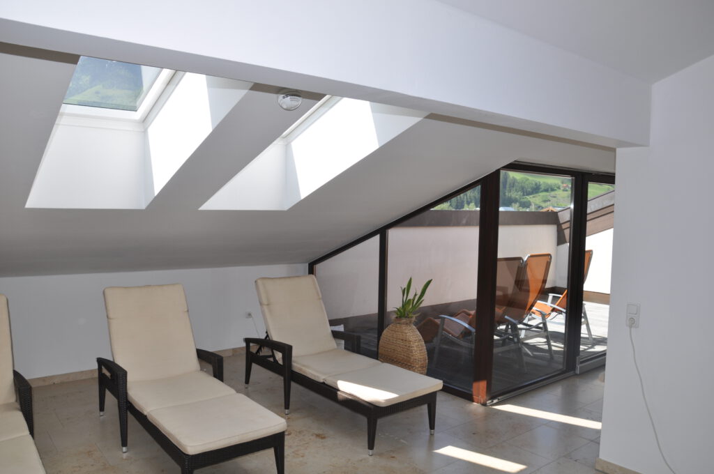 Bright relaxation room with loungers and access to the sun terrace in the Hotel Mittersill