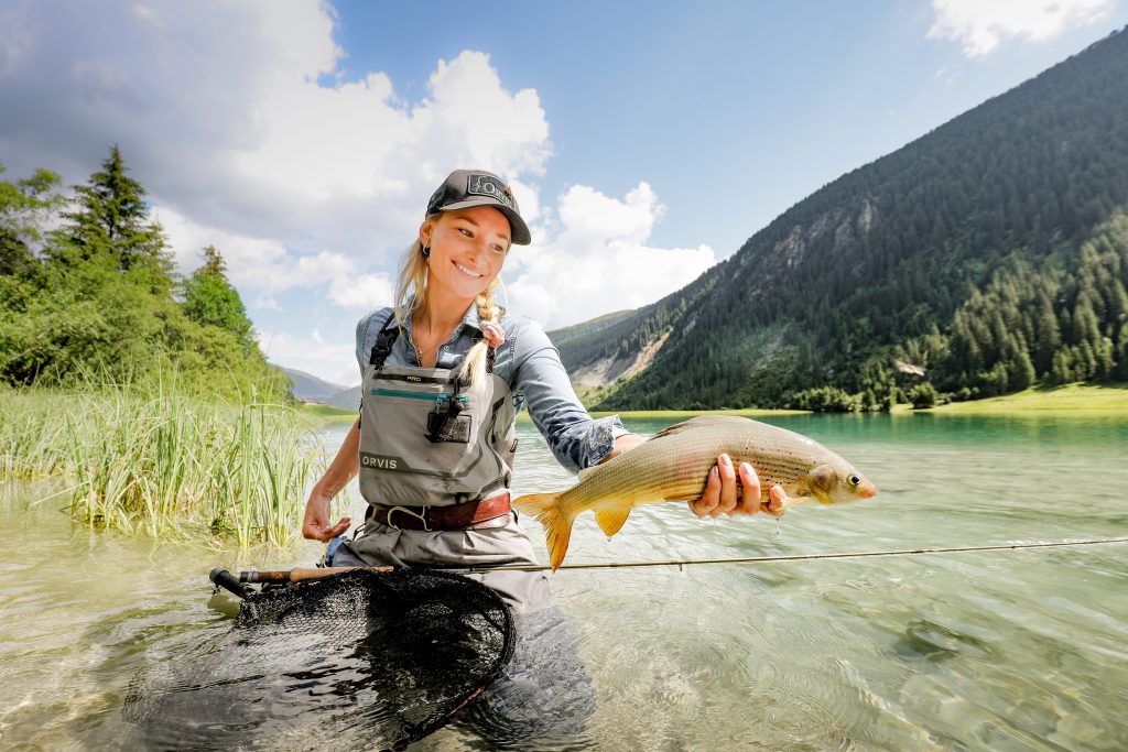 Frau hält gefangenen Fisch in klarem Bergsee
